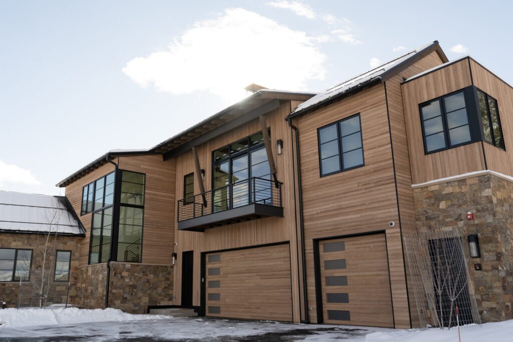 Custom flush cedar garage doors with horizontal glass lites on a snowy Colorado mountain home, built and installed by American Garage Door