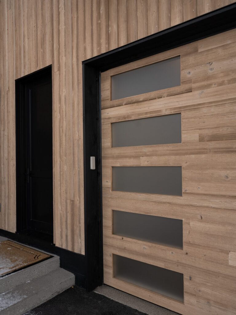 Custom cedar entry door with horizontal glass lites, built to match the home’s custom garage doors by American Garage Door & Gate Systems
