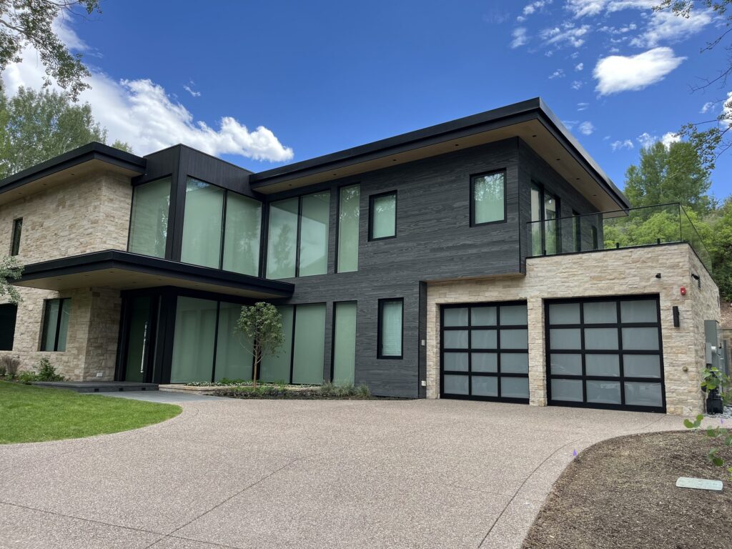 Three full-view frosted glass garage doors with black aluminum frames on a modern Denver home, installed by American Garage Door & Gate Systems