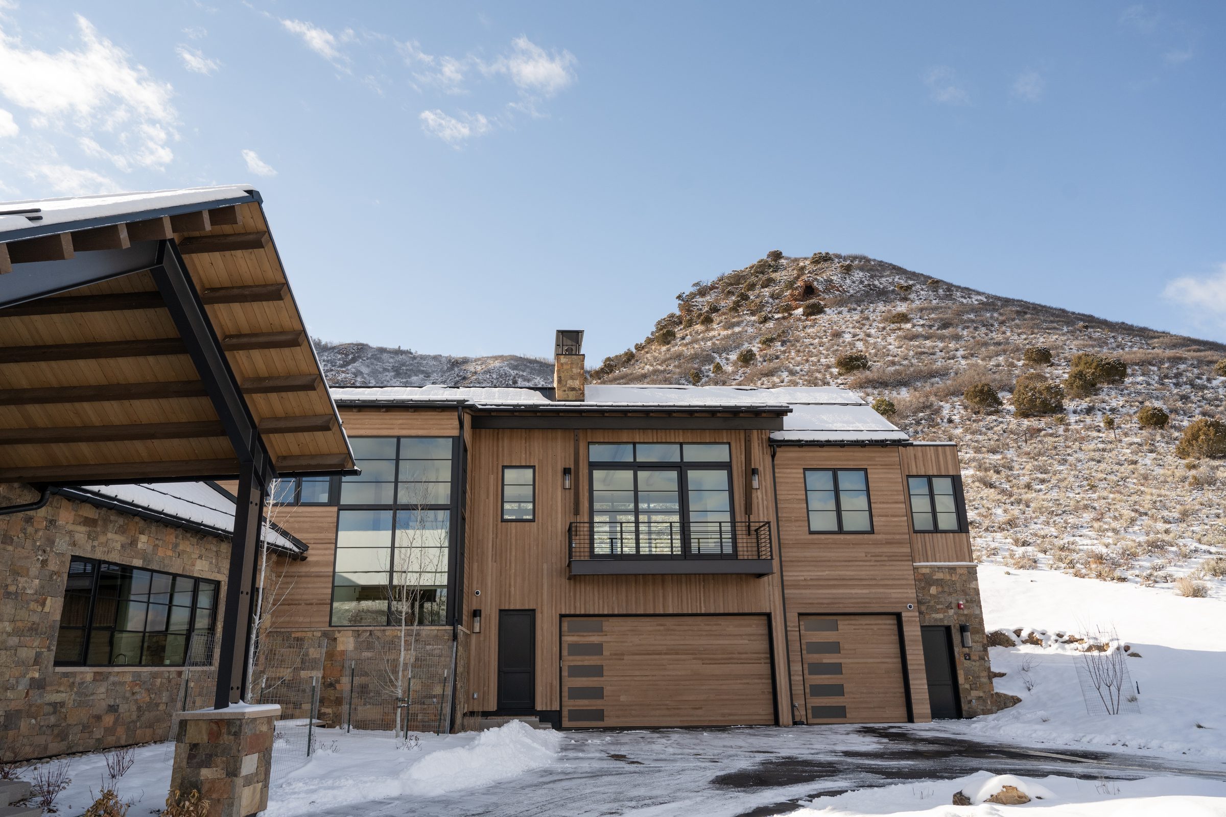 Two custom flush cedar garage doors with black steel accents on a mountain-modern home in the Colorado high country, installed by American Garage Door & Gate Systems