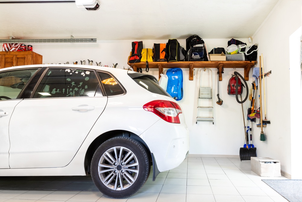 Garage interior organized with storage shelves on white wall.